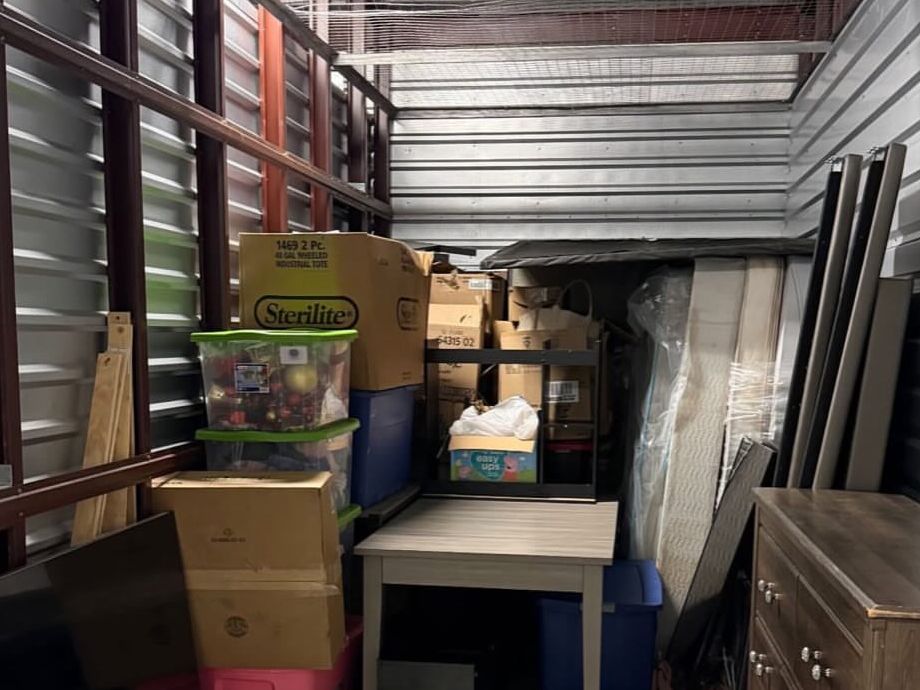 The storage unit she had Maktub load: boxes, bins, a table and a dresser neatly arranged